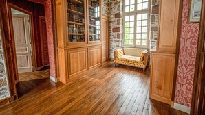 A room with wooden flooring, a built-in bookcase, a patterned wall, and a window with a view. - Demeure Historique - Village D'agon - 800m de la Plage (Agon-Coutainville)
