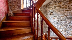 A wooden staircase with a stone wall background and a red patterned wall on the left. - Demeure Historique - Village D'agon - 800m de la Plage (Agon-Coutainville)