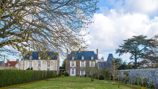 A large, historic stone building with multiple chimneys, surrounded by a well-maintained lawn and stone walls. - Demeure Historique - Village D'agon - 800m de la Plage (Agon-Coutainville)