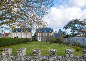 A large, historic stone building with multiple chimneys, surrounded by a well-maintained lawn and stone walls. - Demeure Historique - Village D'agon - 800m de la Plage (Agon-Coutainville)