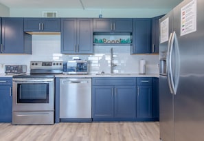 Una cocina moderna con armarios azul oscuro, electrodomésticos de acero inoxidable y un salpicadero de azulejos.