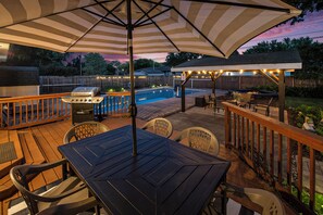 Un patio exterior con piscina, terraza de madera y zona de estar.