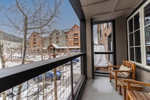 A balcony with wooden benches and a view of multi-story buildings in the background. - Dakota Lodge #8477 by Summit County Mountain Retreats (Keystone)