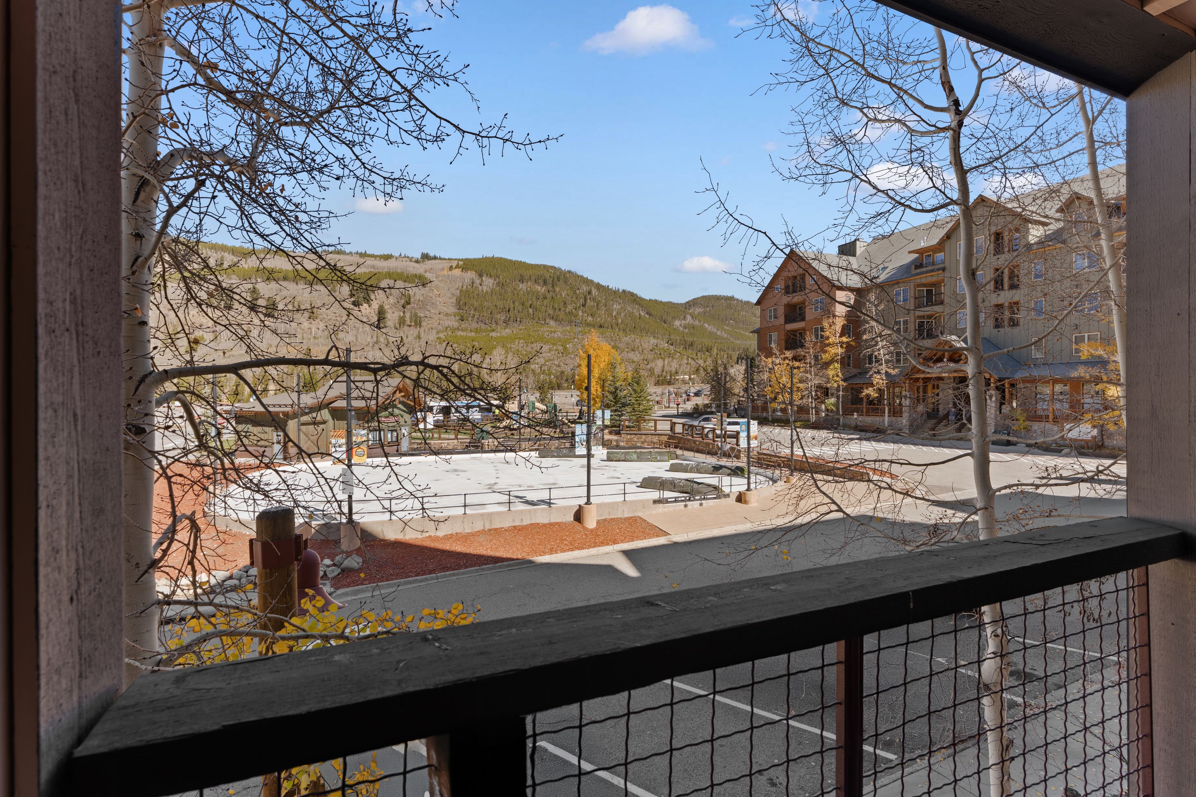 A view from a window overlooking a parking lot, a playground, and a building with multiple floors.