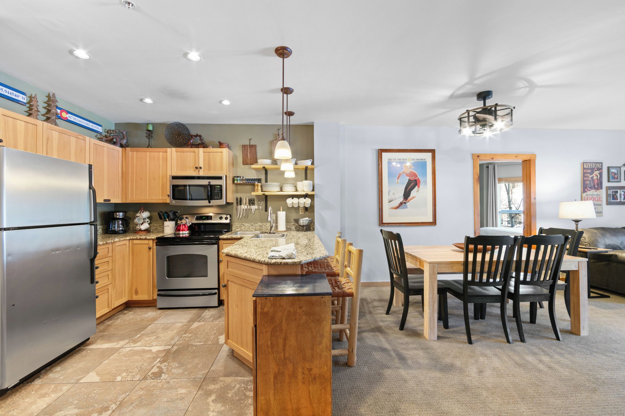 A modern kitchen with wooden cabinets, stainless steel appliances, and a dining area with a table and chairs.
