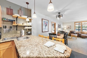 A kitchen with granite countertops, wooden cabinets, and a dining area with a table and chairs. - Dakota Lodge #8477 by Summit County Mountain Retreats (Keystone)