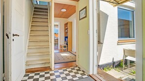 Ein Flur mit Schachbrettmuster, der zu einer Treppe, einem Bücherregal und einem Fenster mit Aussicht führt.