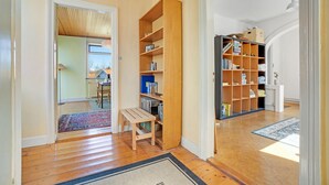 Ein Korridor mit Holzboden, einer Sitzbank und einem Bücherregal voller Bücher.
