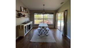 Une cuisine spacieuse avec une table à manger, un plancher en bois et une grande fenêtre donnant sur l’extérieur.