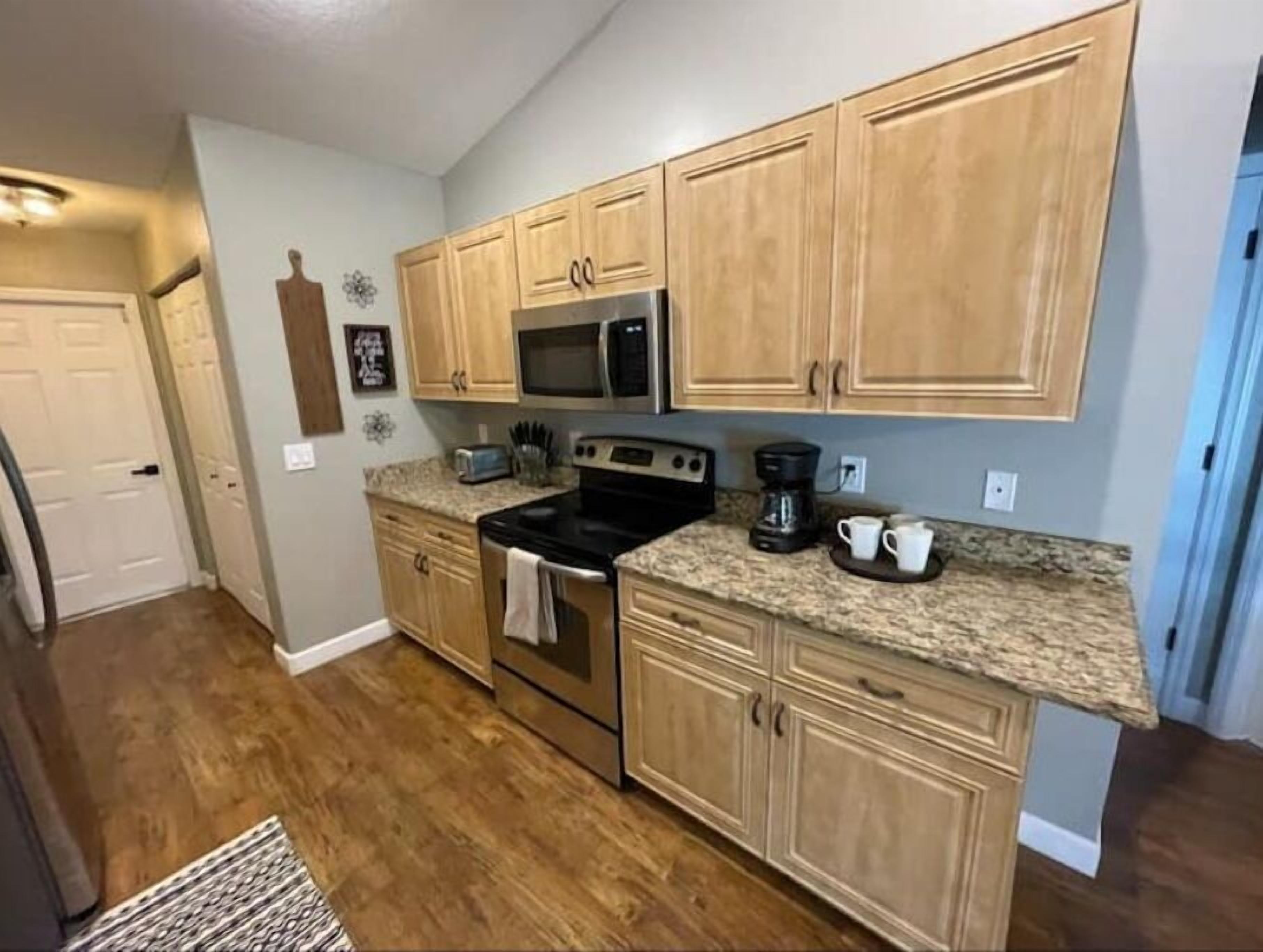 A kitchen with wooden cabinets, a microwave, a stove, and a coffee maker.