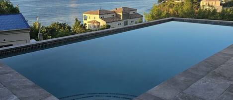 Una piscina con vistas al mar y edificios al fondo.