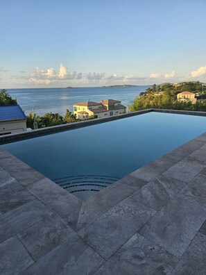 Une piscine avec vue sur la mer et des bâtiments en arrière-plan.