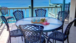 Et rundt bord med stole på en balkon med udsigt over havet.
