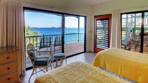 Et soveværelse med balkon, seng, stol og kommode.