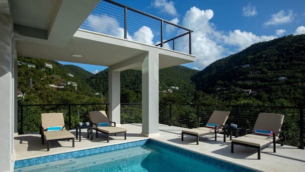 A pool area with lounge chairs and a view of a mountainous landscape. - Tropical Seabreeze- Pool and back up power/solar (Cruz Bay)