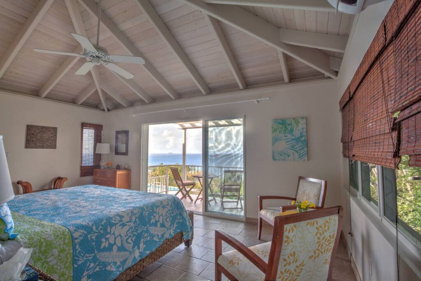 Un dormitorio con cama, una silla, una mesa y vistas al océano.