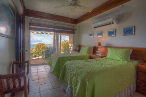 Une chambre avec deux lits, une chaise et une vue sur l’extérieur.