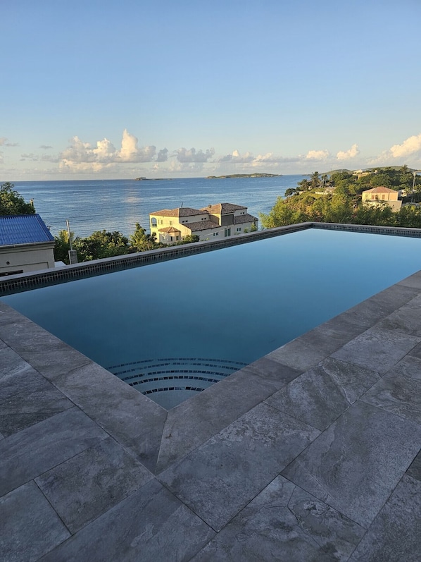 Une piscine avec vue sur la mer et des bâtiments en arrière-plan.