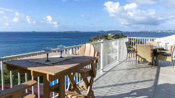 Een terras met houten meubilair en uitzicht op zee.