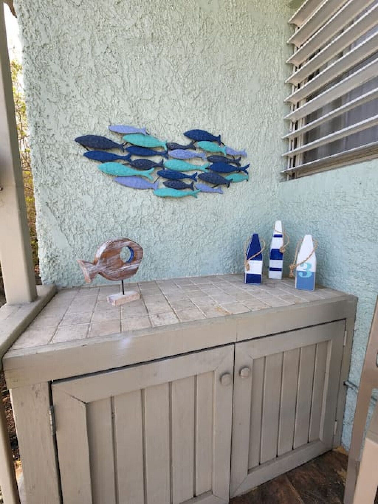 A room with a textured wall, a wooden cabinet, and a fish wall art piece.