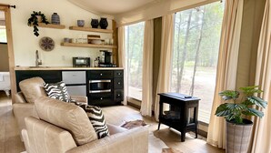 A cozy living room with a leather sofa, a black side table, and a large window with curtains.