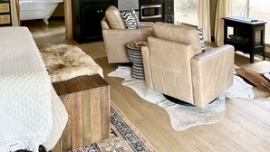 A spacious tented accommodation with a kitchenette, a sofa, a dining table, and a view of the outdoors.