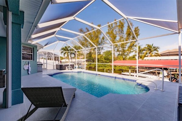 An outdoor swimming pool with a covered area, surrounded by a building with a blue exterior.