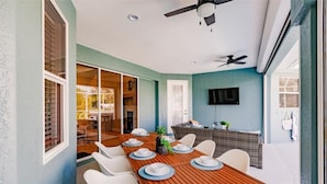 A dining area with a wooden table set for six, white chairs, and a ceiling fan. - Dolphins Cove (Cape Coral)