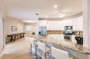 A modern kitchen with white cabinets, a granite countertop, and a built-in microwave.