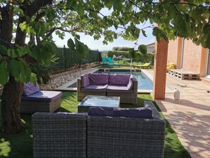 A poolside area with wicker furniture, a small pool, and a view of the landscape.
