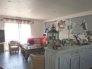 A living room with a red sofa, wicker chairs, a coffee table, and a cabinet with decorative items.