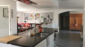 Eine moderne Küche mit Kochinsel, ein Essbereich mit einer Couch und ein Wohnzimmer mit Kamin.