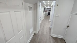 Un pasillo con puertas blancas y una zona de cocina al fondo.