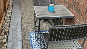Un patio con una mesa y sillas, una reja de madera y un edificio de ladrillo.