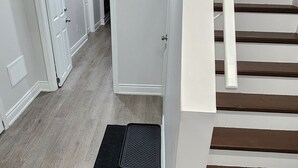 Una escalera con acabado de madera y un felpudo negro al final.