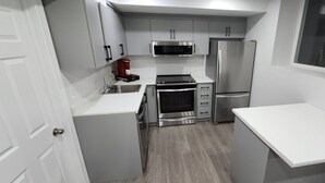 Una cocina compacta equipada con microondas, horno, refrigerador y cafetera.