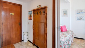 Une chambre d’hôtel avec une porte en bois, un lit recouvert d’une courtepointe à motifs floraux et une petite poubelle.