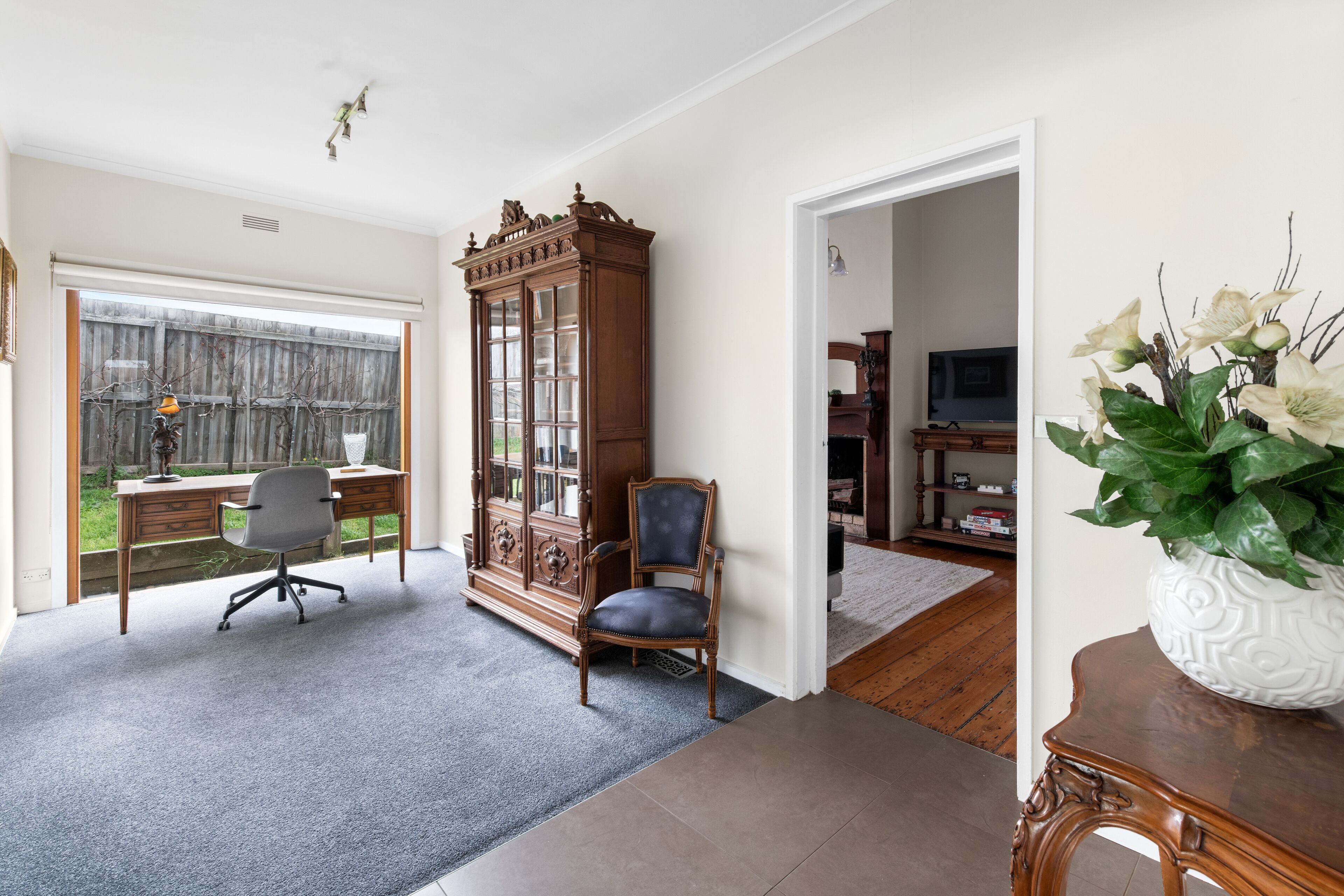 A room with a desk, a chair, a cabinet, and a large window.