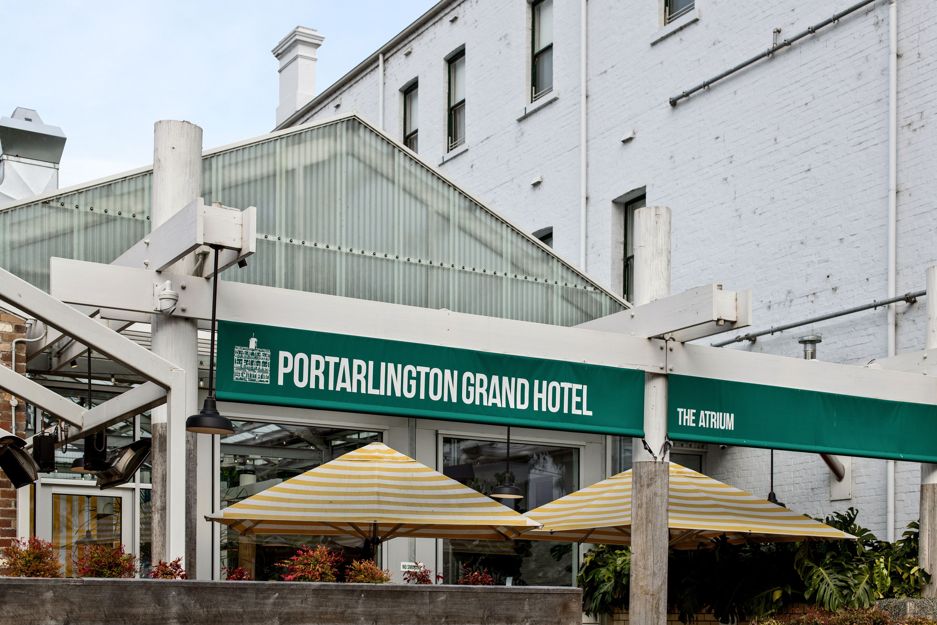 The exterior of the Portarlington Grand Hotel with a green awning, outdoor umbrellas, and a visible entrance.