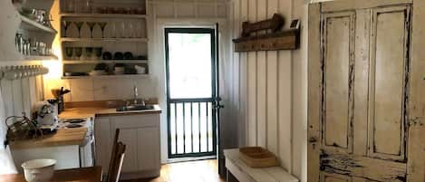 Una cocina compacta con armarios de madera, un lavamanos y una zona de comedor con banco y mesa.