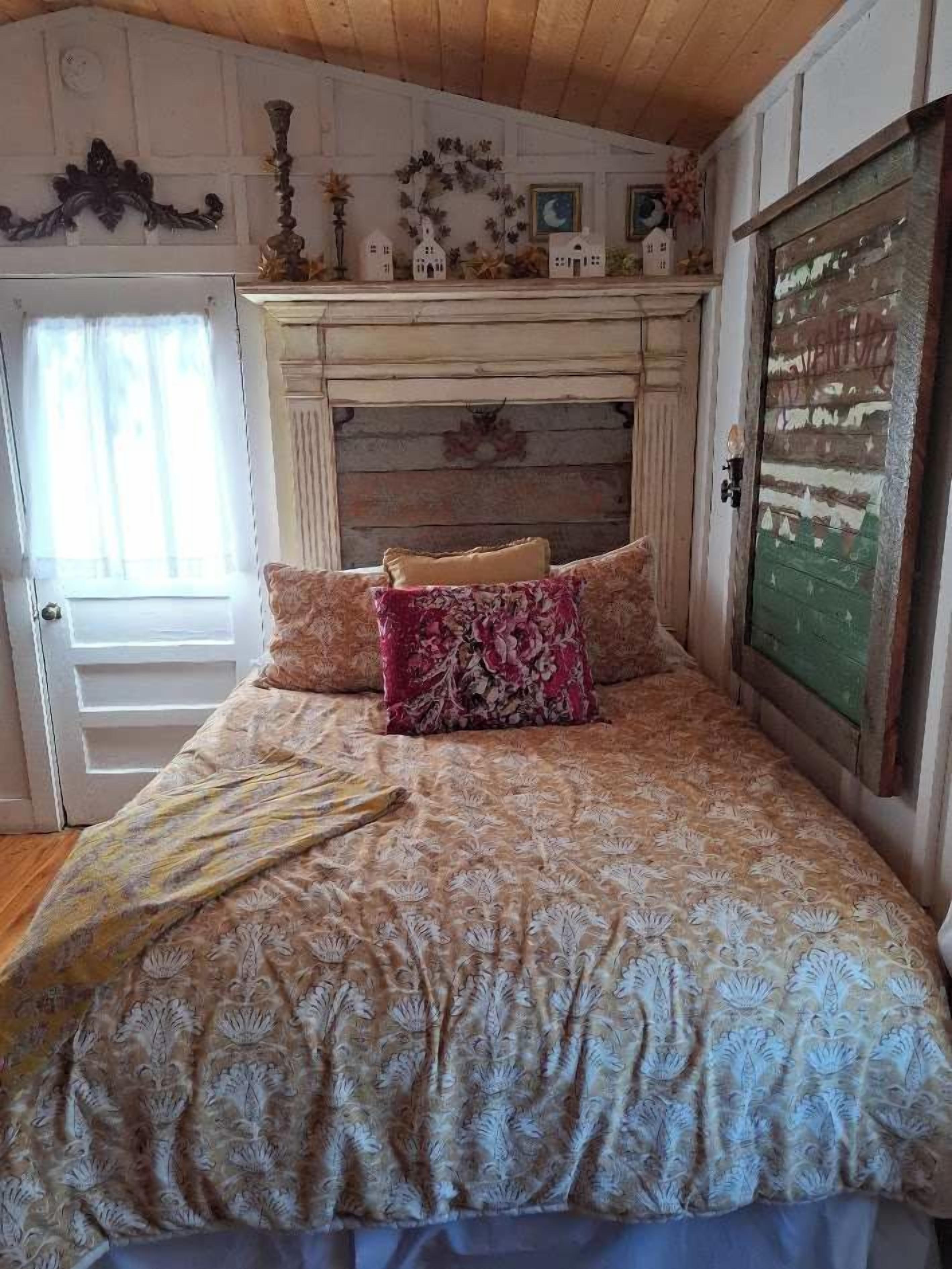 A bedroom with a wooden headboard, a bed with patterned bedding, and a door with a rustic design.