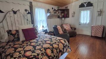 A room with a bed, a chair, a wooden cabinet, and a door.