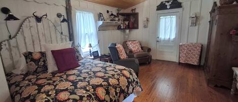 Una habitación con una cama, una silla, un armario de madera y una puerta.