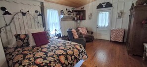 A room with a bed, a chair, a wooden cabinet, and a door.