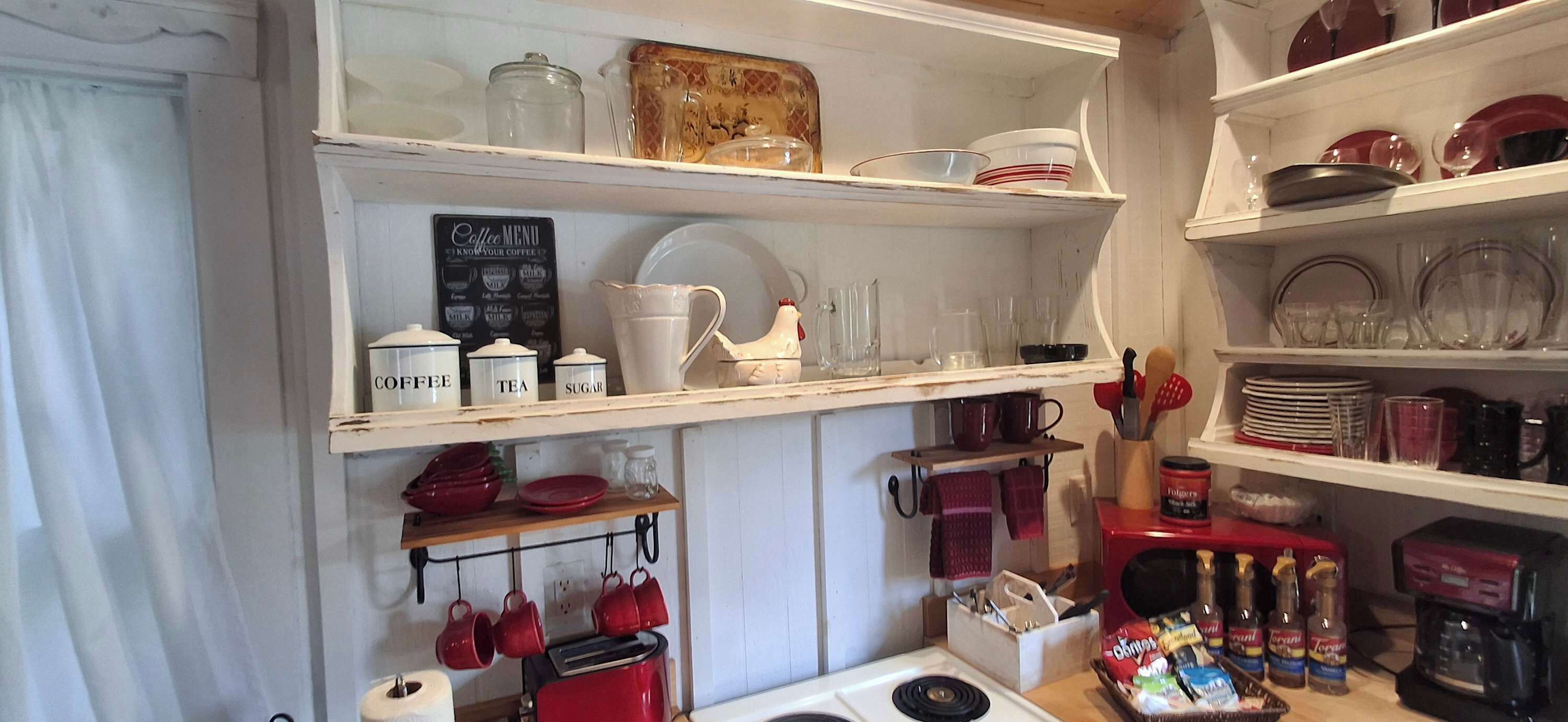 A kitchen with shelves holding various kitchenware, a coffee menu sign, and a toaster.