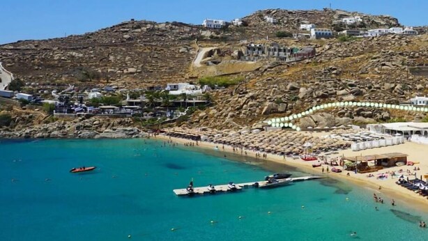 Une zone côtière avec une plage, des bateaux et des bâtiments situés sur une colline.