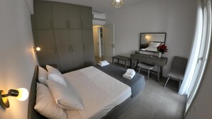 Une chambre d’hôtel comprenant un lit, une table de chevet, un bureau, une chaise, une armoire et un miroir.