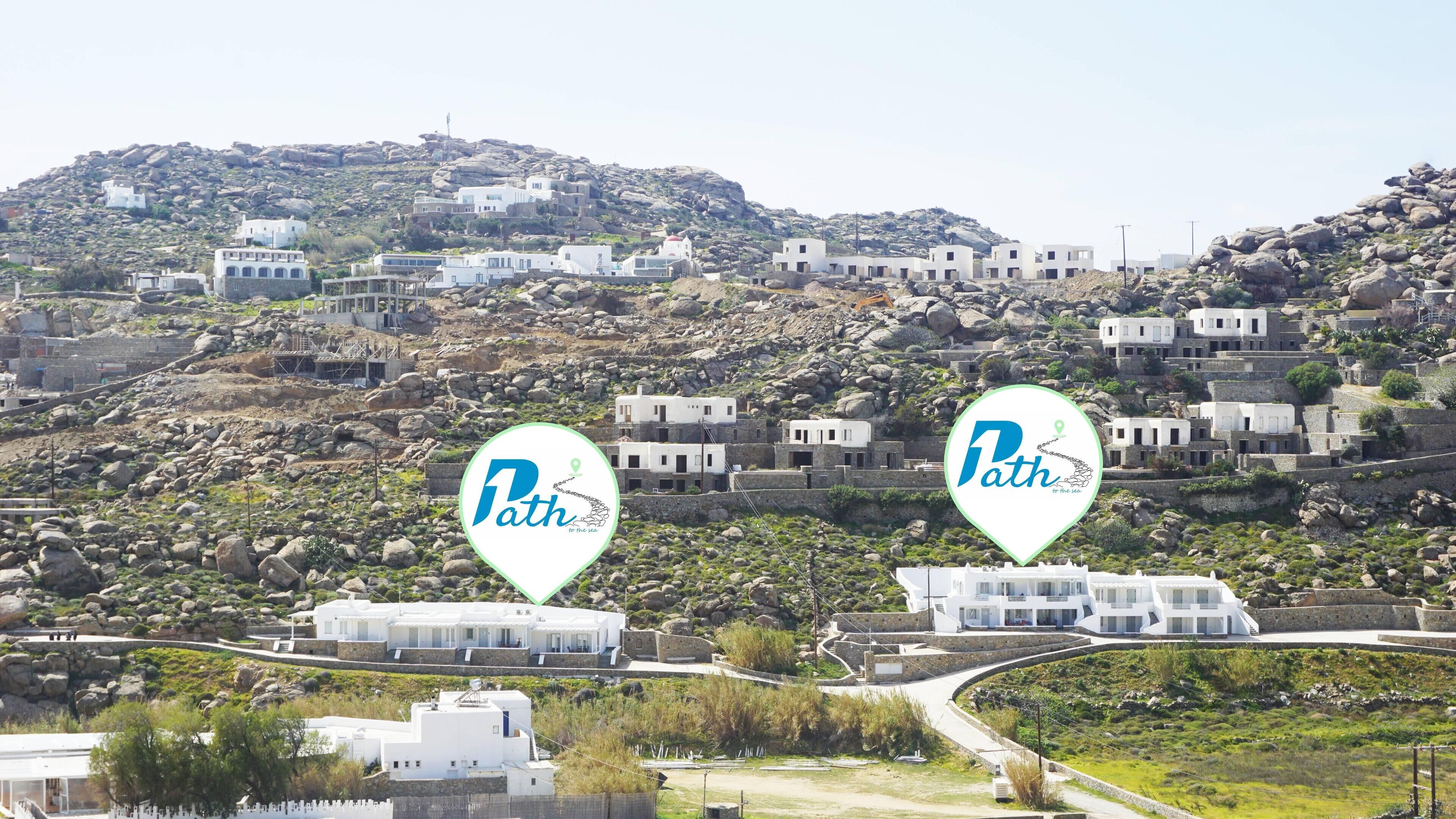 Un pueblo en una ladera con edificios blancos, un camino serpenteante y dos indicadores de ubicación que dicen 'Path'.