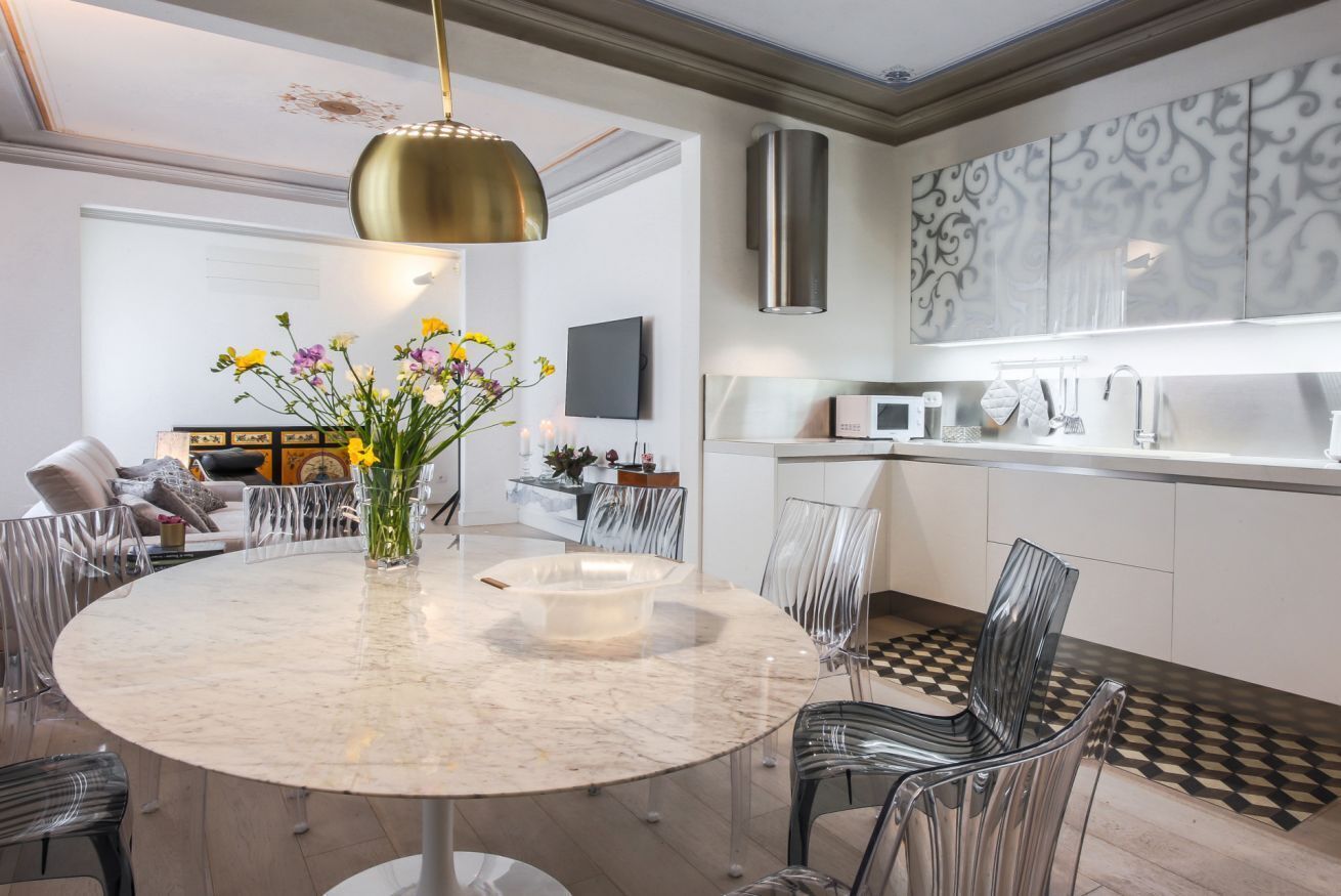 A modern kitchen with a marble island, stainless steel appliances, and a decorative wall panel.