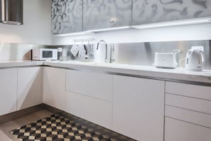 A modern kitchen with white cabinets, a microwave, a toaster, and a kettle. - Apartments Florence - Boboli Deluxe (Firenze)